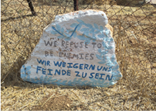 Stone painted with the words 'We refuse to be enemies' in English and German.